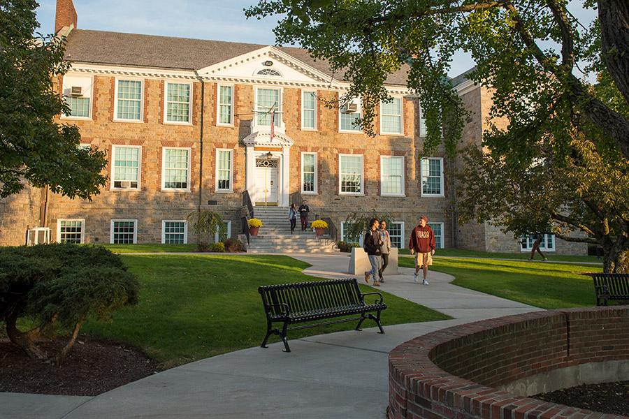 A student in an Iona hoodie leads two individuals on a campus tour and walk past Doorley hall.