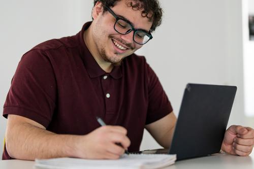 A student smiles and works on his computer.