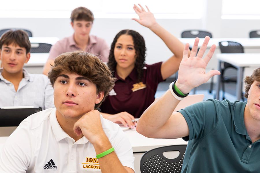 Students raise their hands in a business administration class.