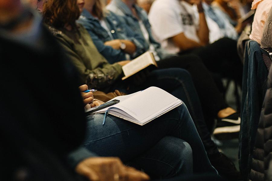 Several people are sitting in a row taking notes.