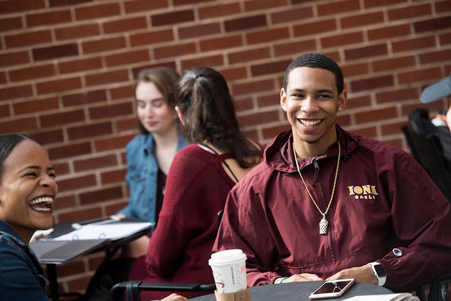 Two students sit a table at starbucks, drink coffee and laugh.