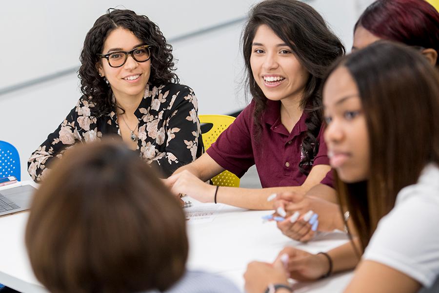 Members of the Hynes Institute staff sit at a table at Gael ventures and work with female students.