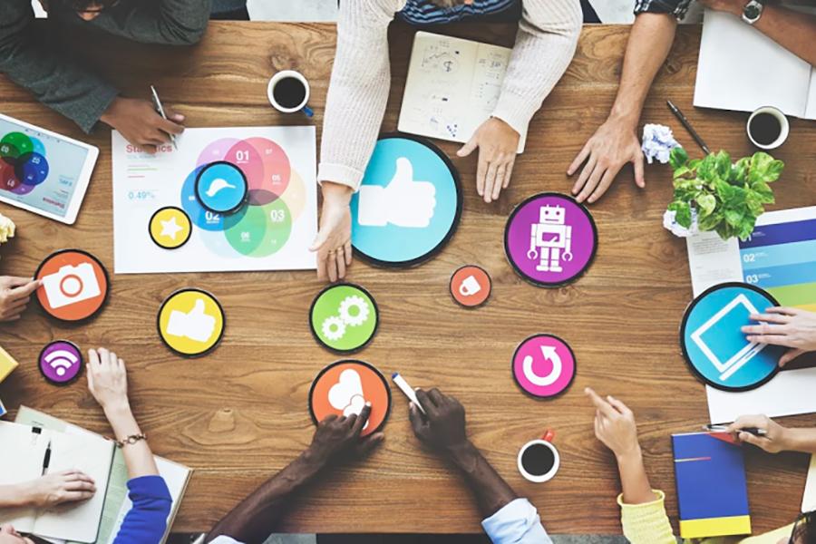 People collaborate on a table covered with circular marketing symbols.