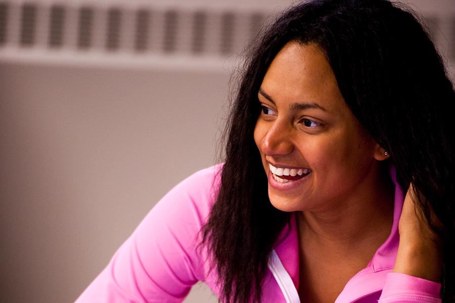 A student in a pink hoodie smiles brightly in a marketing class. 