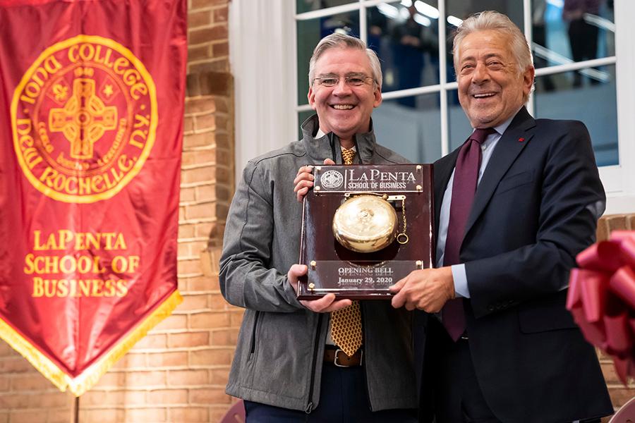 Iona University president Seamus Carey, Ph.D., and Mr. LaPenta hold up the LaPenta opening bell at the ribbon cutting.