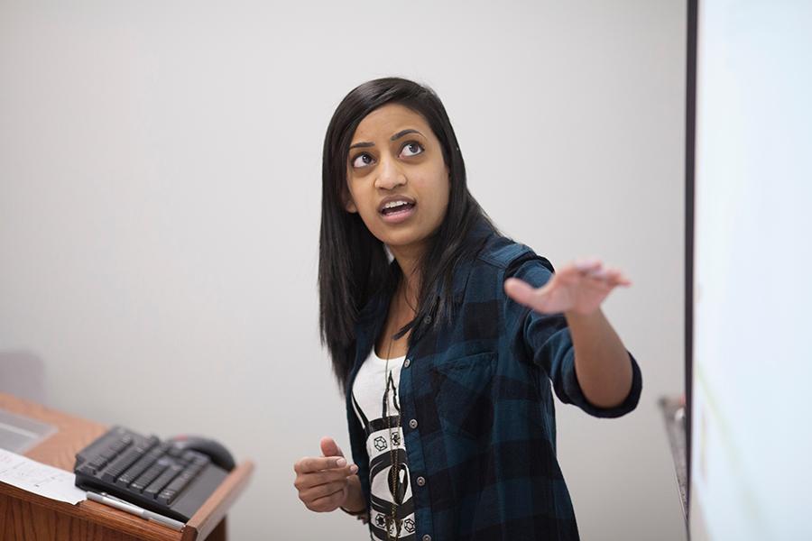 A math professor points to the whiteboard.