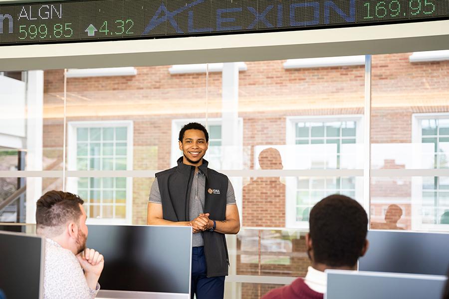 A student gives a presentation in front of the ticker in the LaPenta School of Business.