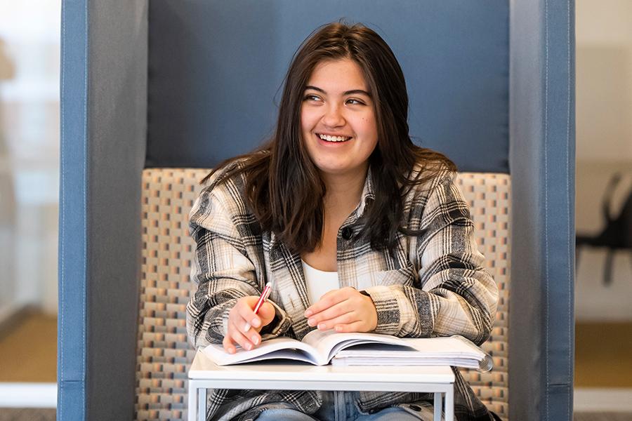 A student studies out of a textbook and smiles.