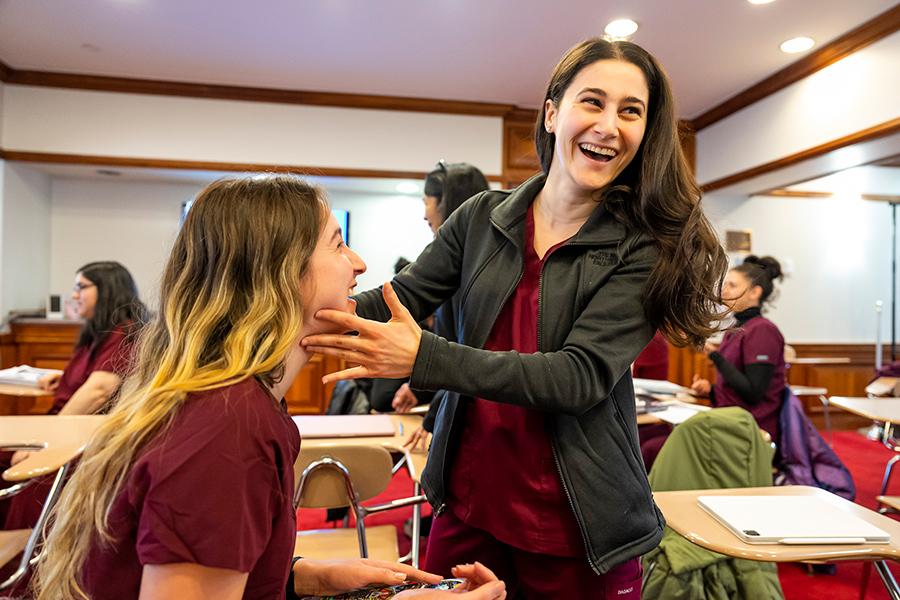 Two speech-language pathology students practice together and smile.