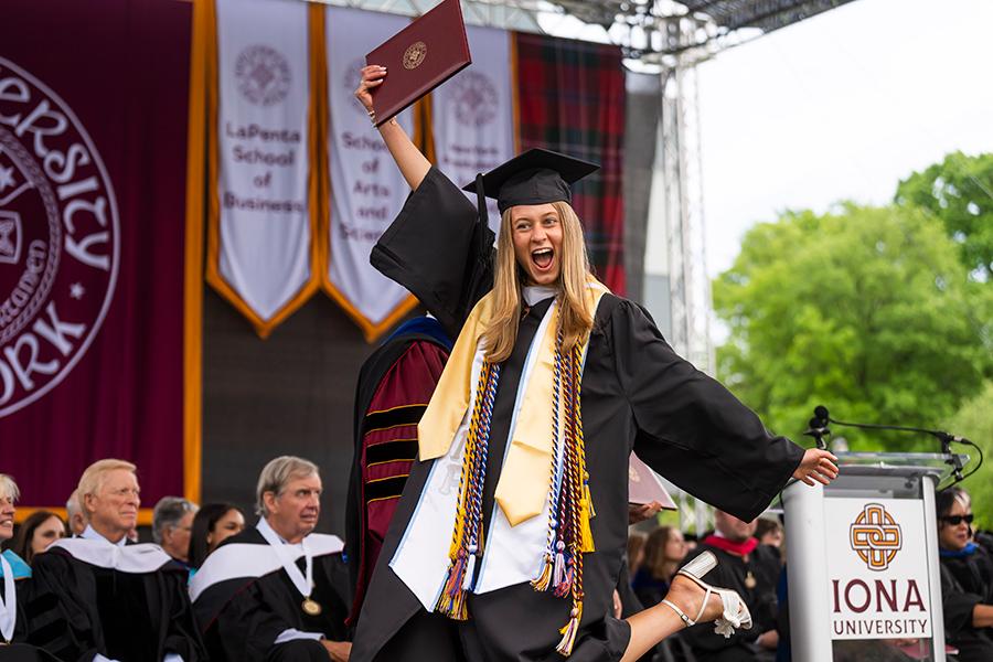 A student celebrates as she walks across the Commencement stage.