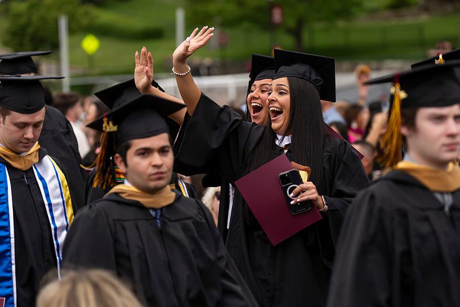 Two graduates wave to their families in the crowd.