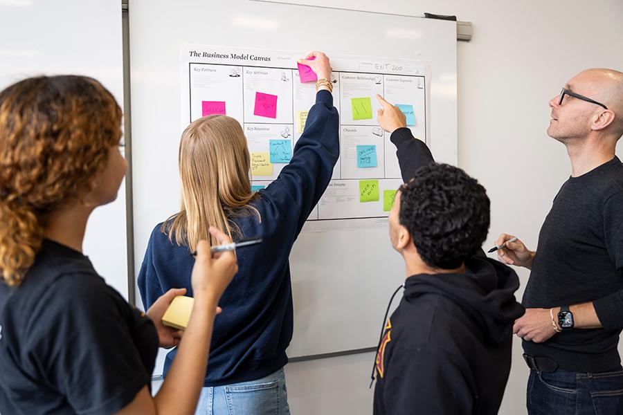 Students and Chrisoph Winkler work at a whiteboard at the Hynes Institute.