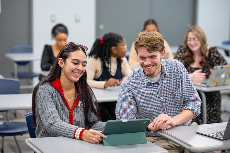 Students work together on a laptop in a classroom.