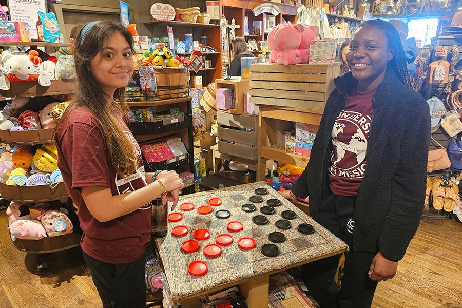 Two Iona in Mission students playing checkers at a quaint toy store.