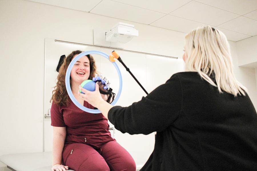 An OT student practices handing a ball through a circle.