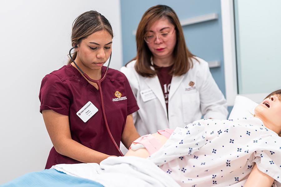 A nursing student practices on a mannequin with a professor.