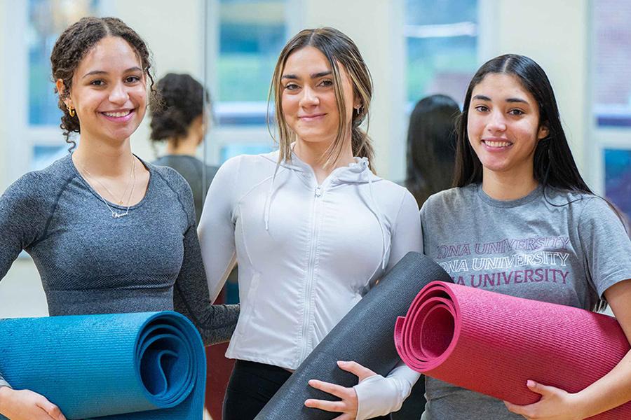 Three students with yoga mats after a yoga class.