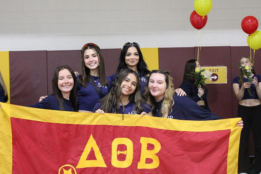 Five members of Delta Theta Beta hold their banner in Mulcahy.