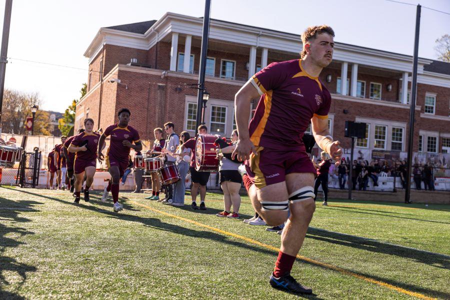 The rugby team runs onto Mazzella field.