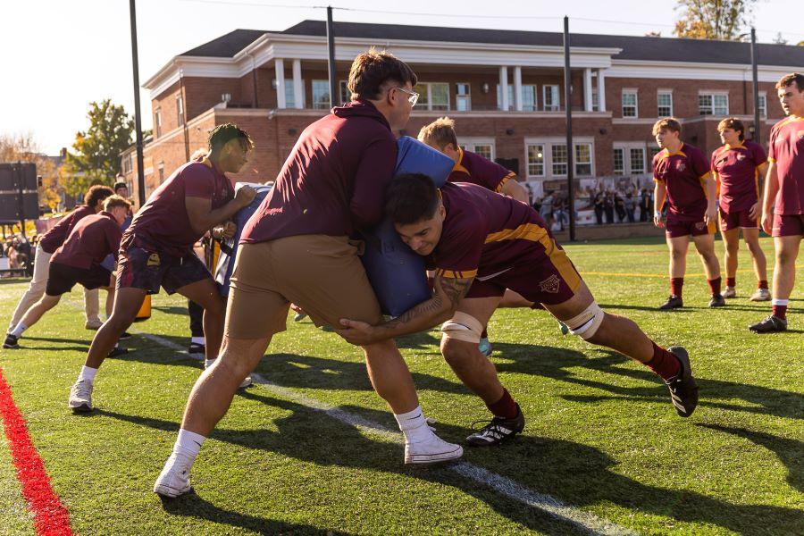 The rugby team running tackling drills before a game.