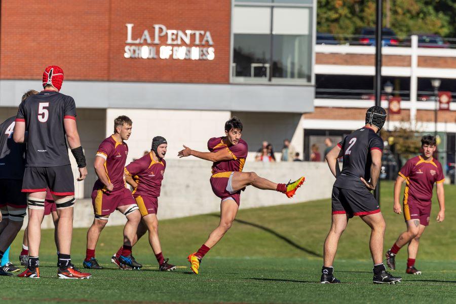 A rugby player kicks the ball down field. 