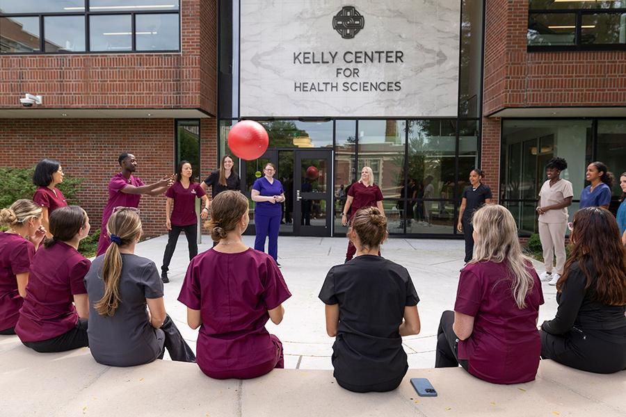 OT students practice tossing a ball outside of the Kelly Center for Health Sciences.