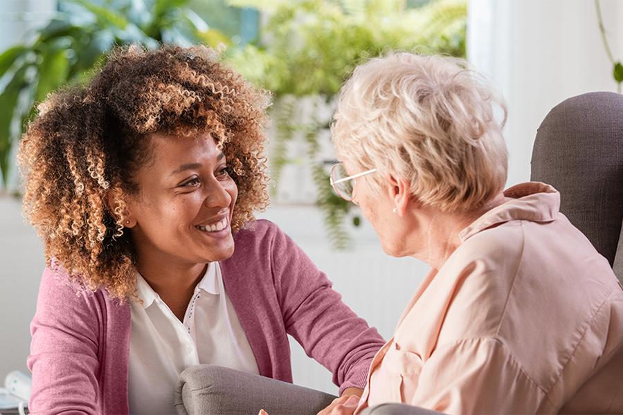 A social worker works with an older client and smiles.