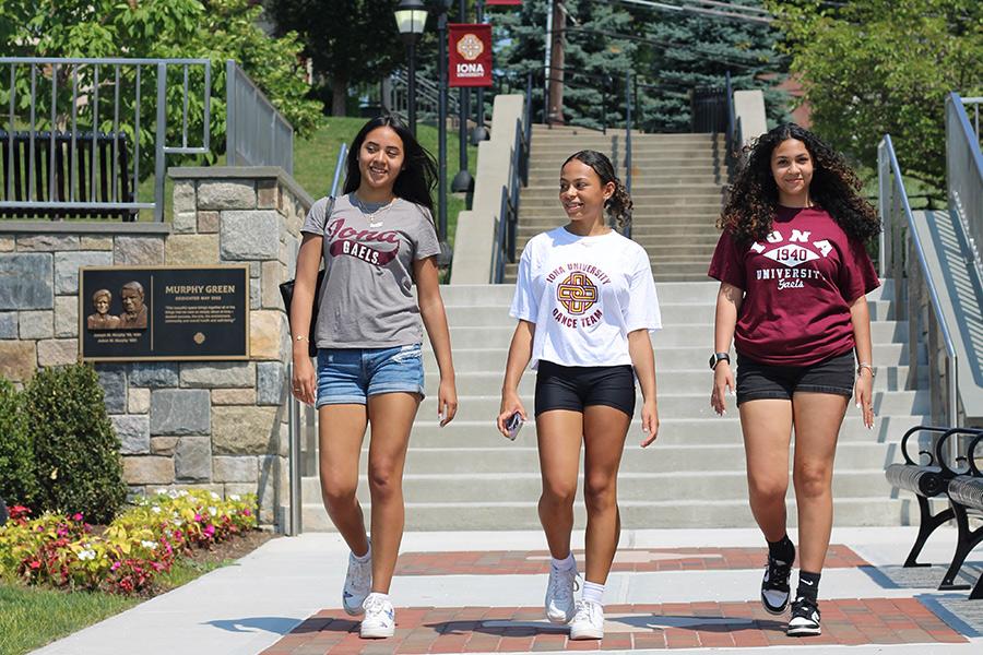 Three students walk by the Murphy Green on a sunny day.