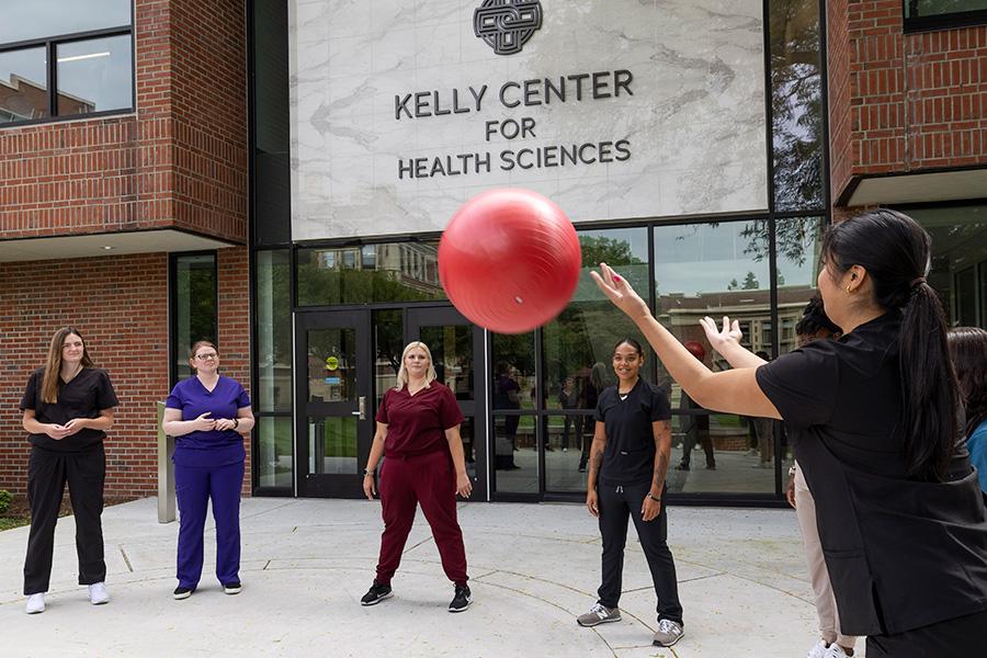 OT students practice movement with a ball outside of the Kelly Center.