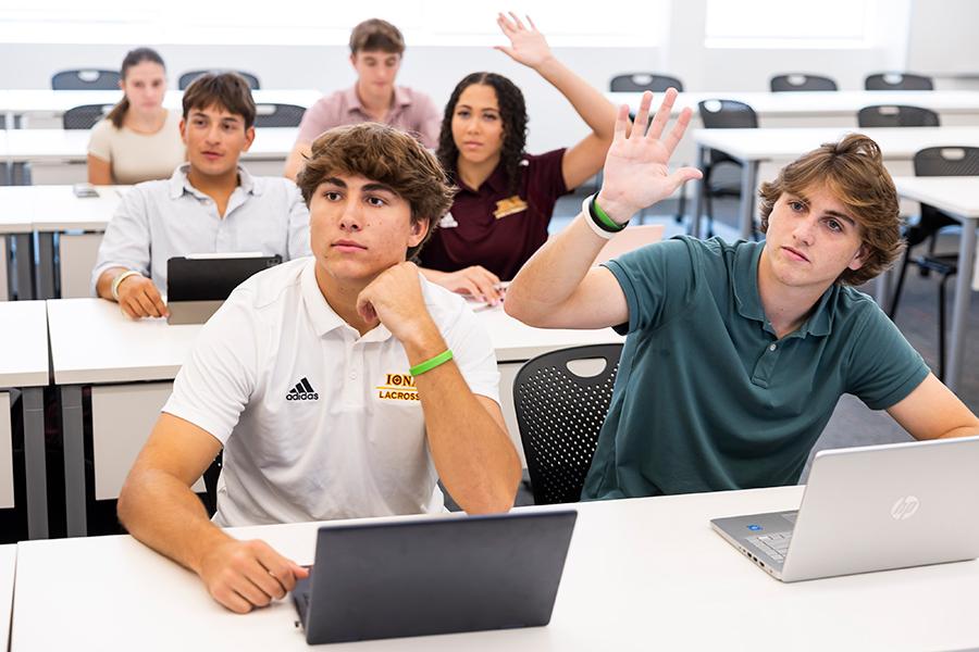 Students raise their hands in a business administration class.