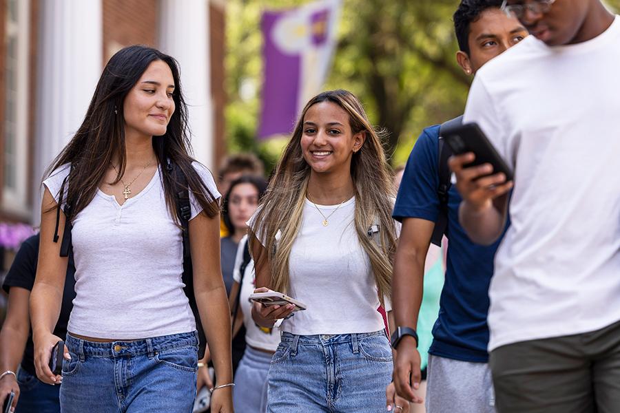 Two students walk and smile on campus.