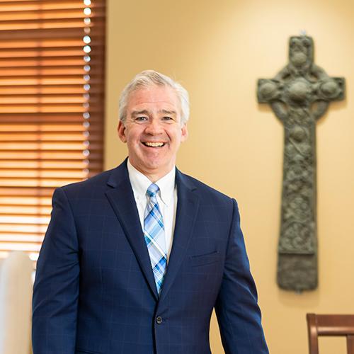 President Carey in his office with a Celtic Cross on the wall.