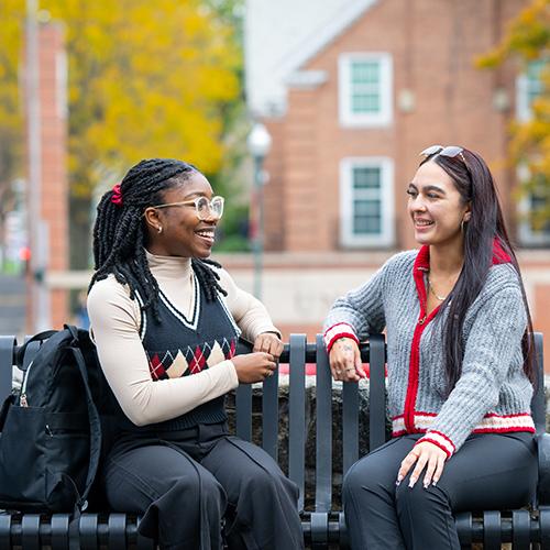 Students sit on a bench and talk.