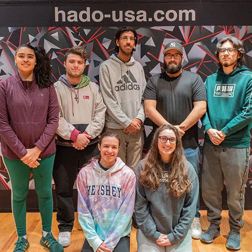 Iona University HADO players in front of the HADO banner.