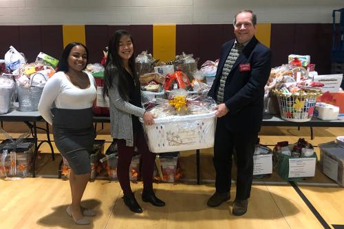 Carl Procario-Foley, Faith Krefft and another OMM student help with the giving baskets during Thanksgiving.