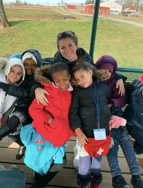 Gina Tomaj with her students on a bench outside at a farm.