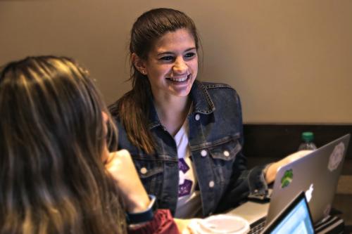 A student sits with her friends at a table in Starbucks.