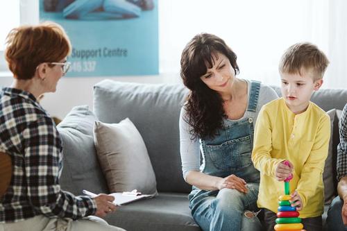 A therapist works with a family including the mother and young son.