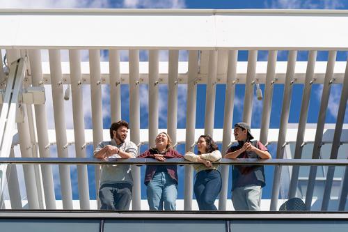 Four students smile and laugh on the terrace of the LaPenta School of Business.