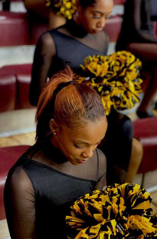 A BSU dancer with pom poms looks down and smiles.