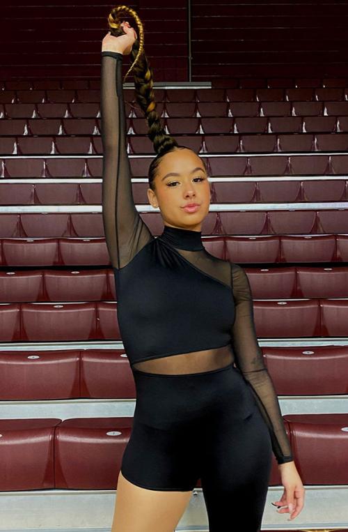 A BSU dancer lifts her braid and looks directly into the camera.