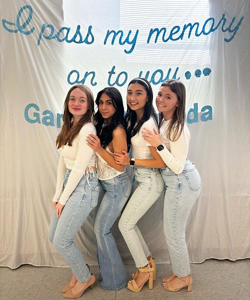 Four members of Gamma Lambda Rho in front of a banner.