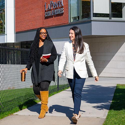 Two female students walking outside of LaPenta Business School