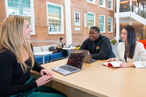 Three students work at a table in the LaPenta School of Business.