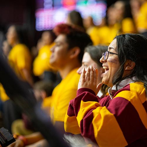 A person cheers at a basketball game.