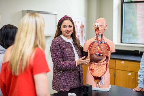 A professor demonstrates on an anatomy torso for a health and wellness class.