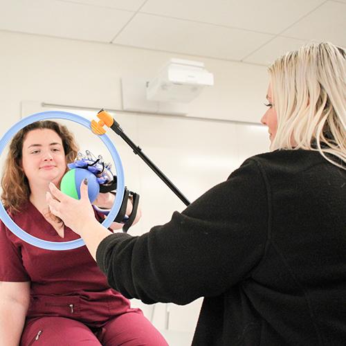 An OT student practices with hand mobility equipment.