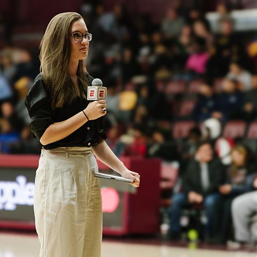 A student sports anchor at a basketball game.