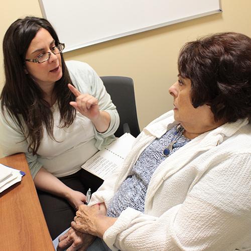 A speech language pathologist student works with a woman on pronunciation.