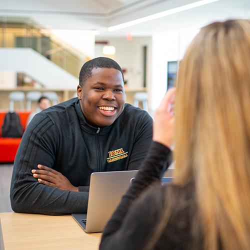 A student smiles in the atrium of the LaPenta School of Business.